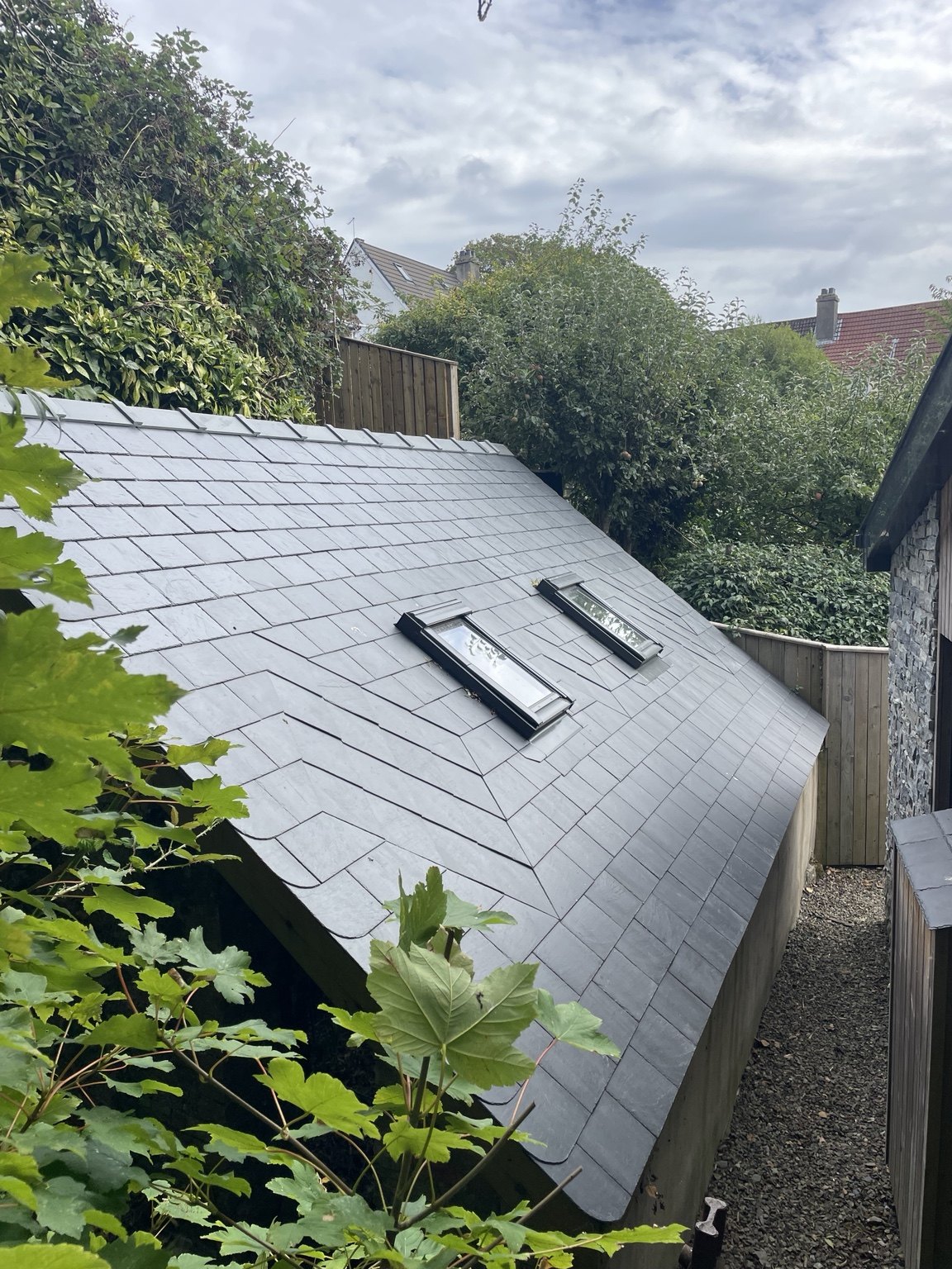 Slate roof with roof windows surrounded by greenery
